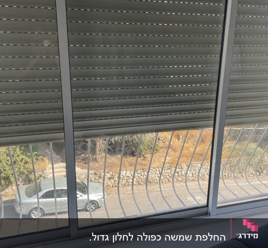 חלון זכוכית עם תריסים סגורים ומעקה מתכת